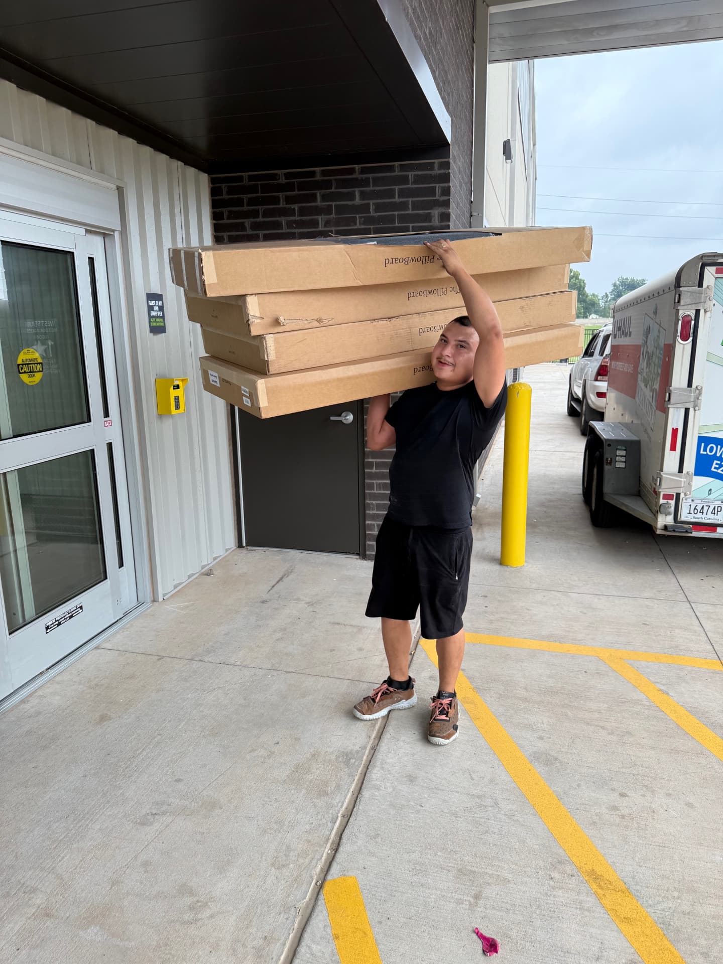 Top Dawg Movers mover carrying stacked boxes at an Oklahoma City storage facility