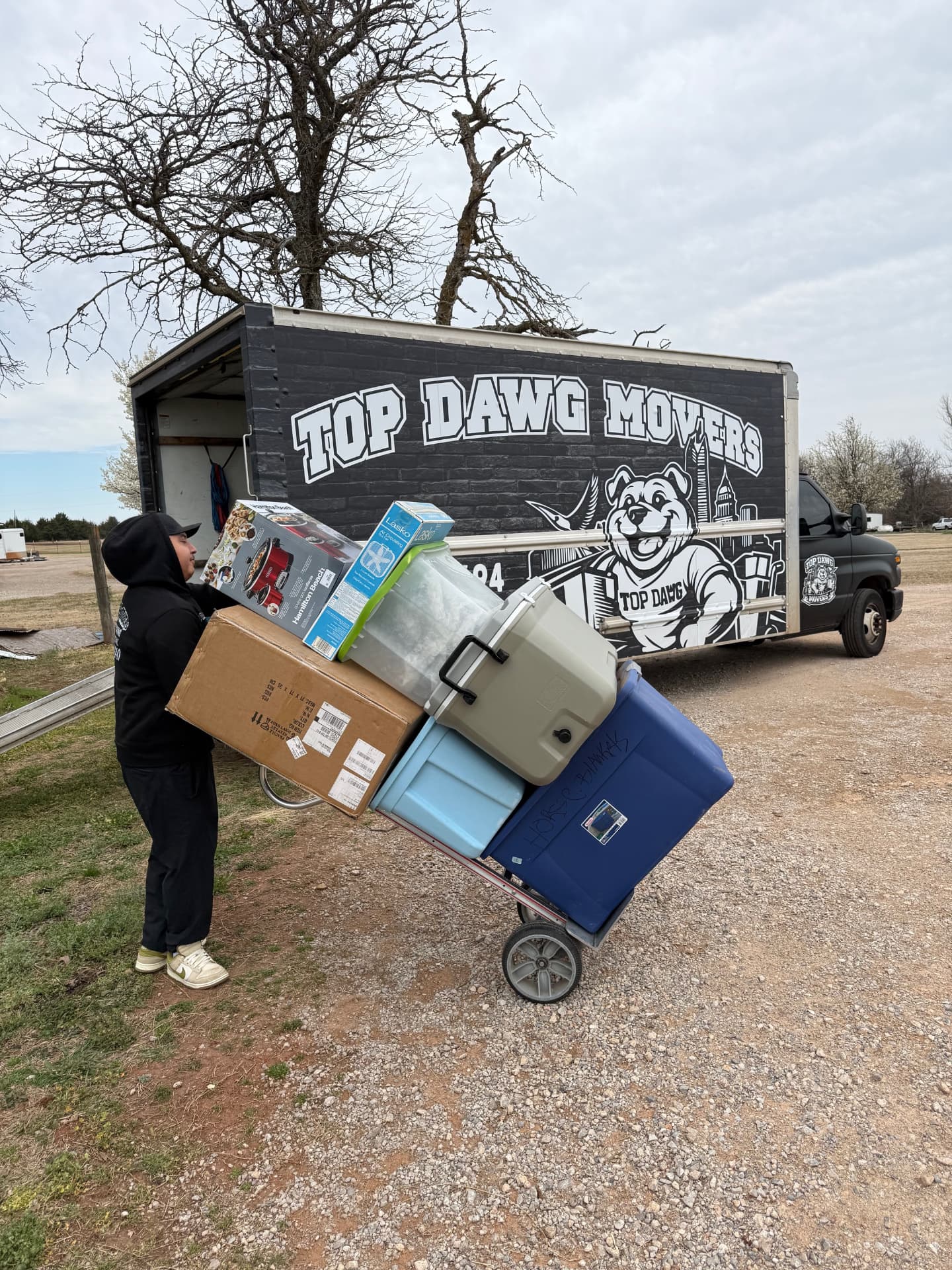 Top Dawg Movers crew member rolling a loaded dolly to the moving truck on a job near Bethany, OK
